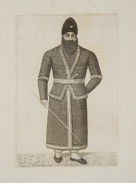 A greyscale etching depicting Mirza Aboul Hassan Khan; a bearded Khan, wearing a tailored coat and conical turban, stands square to frame, holding a pole in his right hand and the other behind his back.